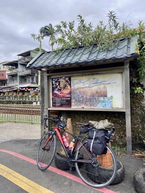 一台單車靠在兩個紅色三角錐旁邊，外套固定在單車的馬鞍袋上