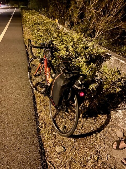 黑夜中一台單車停靠在路肩的草叢裡