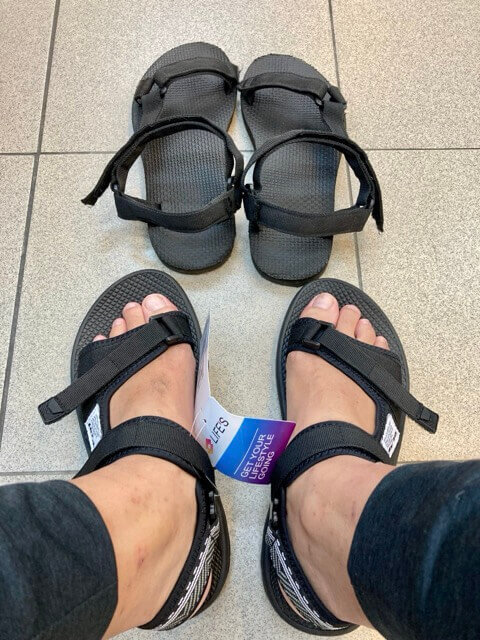 一雙腳穿著有吊牌的涼鞋，旁邊有一雙舊涼鞋