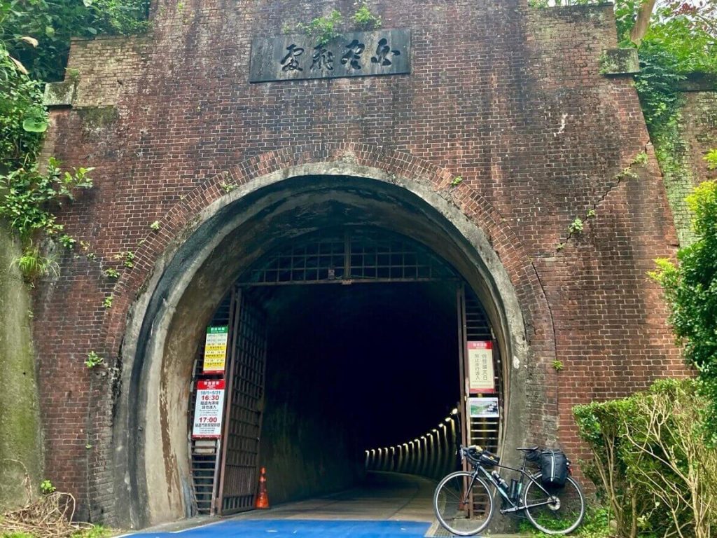 紅色磚牆和鐵門的隧道入口旁停一輛腳踏車