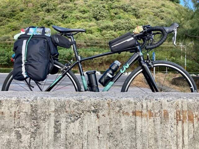 一台單車靠在水泥矮牆外側，寶特瓶固定在單車的馬鞍袋上